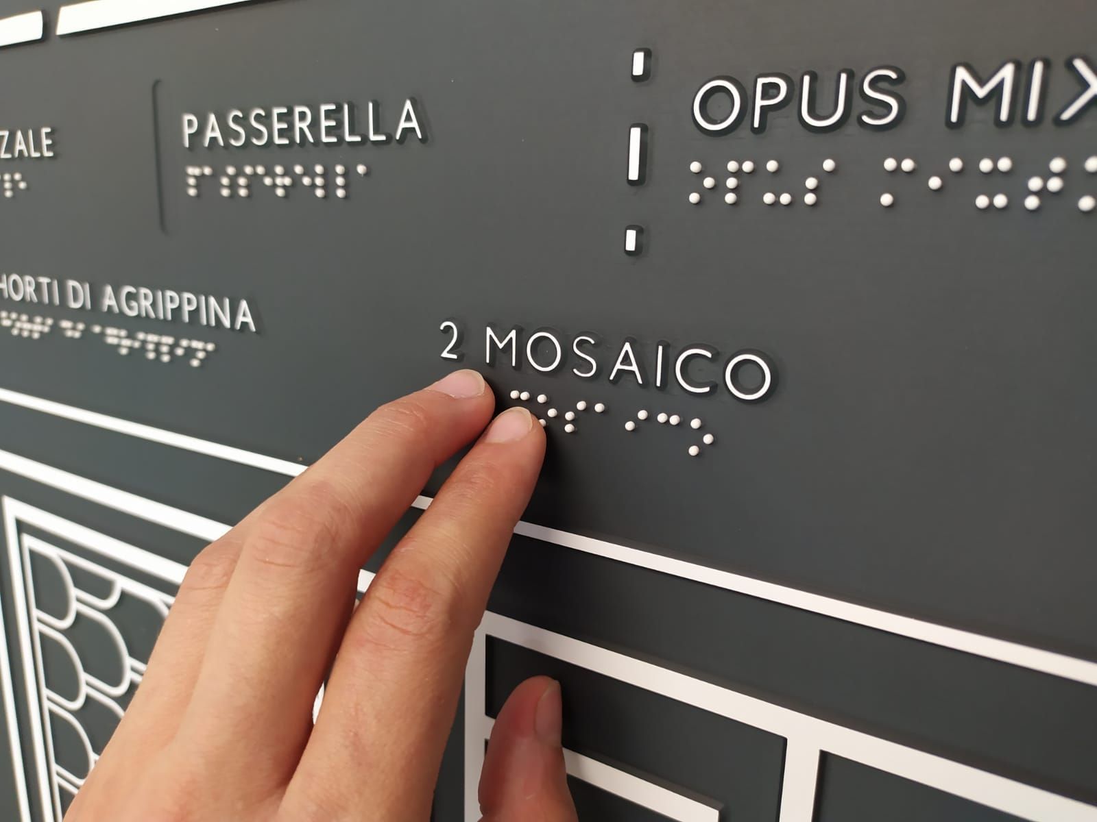 uno mano tocca una targa in scrittura braille realizzata da incisoria vicentina
